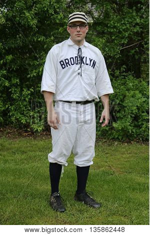OLD BETHPAGE, NEW YORK - MAY 22, 2016: Baseball player in 19th century vintage uniform during old style base ball play following the rules and customs from 1864 in Old Bethpage Village Restoration
