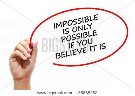 Man writing IMPOSSIBLE IS ONLY POSSIBLE IF YOU BELIEVE IT with marker on transparent wipe board.