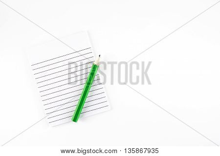 Top view of Ruled paper notepad with green pencil on white background Leave space for adding your content..