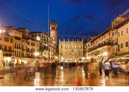 Verona Italy - May 07 2016: Some people walking on the Market square against the backdrop of the Maffei Palace and Gardello tower evening time