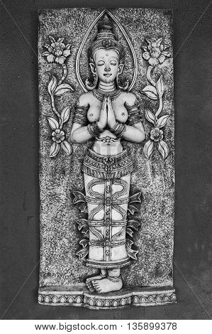 Carving in Thailand of a naked religious woman praying or meditating