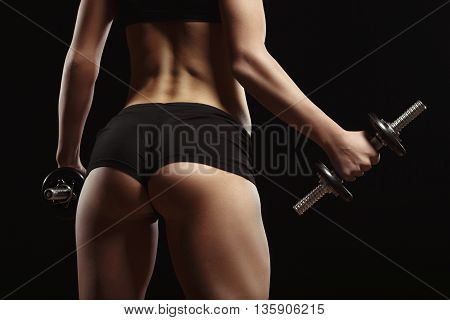 Sexy fitness ass close-up. Part of fitness body on a black background. Perfect female sports figure. Fitness woman posing in the studio. Fitness photo shoot in the studio. Fitness bikini