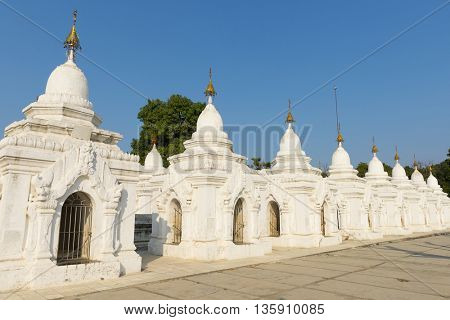 Kuthodaw Pagoda contains the worlds biggest book. There are 729 white stupas with caves with a marble slab inside - page with buddhist inscription. Mandalay, Myanmar