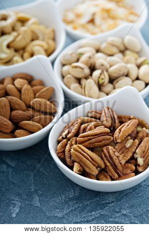 Variety of nuts in small white bowls healthy snacks