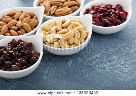 Variety of nuts and dried fruits in small white bowls healthy snacks