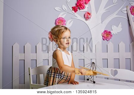 Beautiful little girl playing toys.Blue-eyed blonde.White chair.Children's room. Happy small girl portrait.