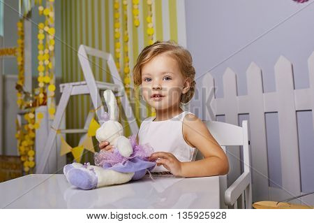 Beautiful little girl playing toys.Blue-eyed blonde.White chair.Children's room. Happy small girl portrait.