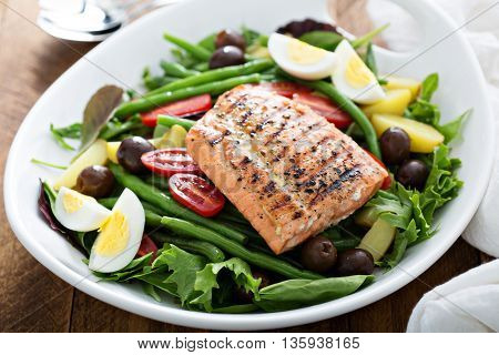 Grilled salmon nicoise salad with potatoes, olives, salad leaves