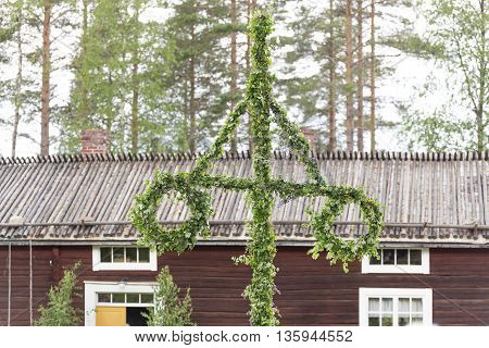 Swedish Traditional Midsummer Pole (Maypole) with a building in the background.