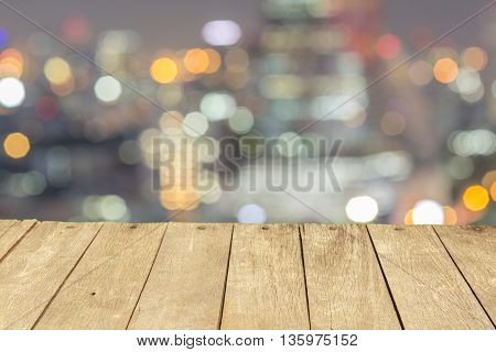 Empty wooden table or plank with bokeh of light from city tower on background for product display.