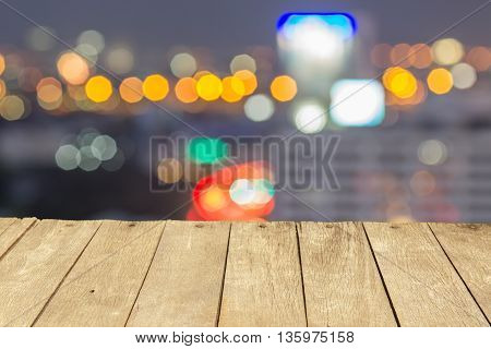 Empty wooden table or plank with bokeh of light from city tower on background for product display.