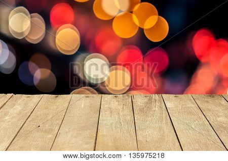 Empty wooden table or plank with bokeh of light from road or street with city tower on background for product display.
