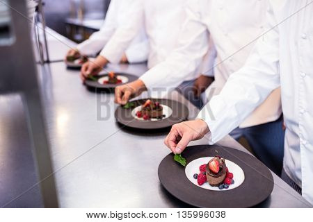 Team of chefs finishing dessert plates in the kitchen