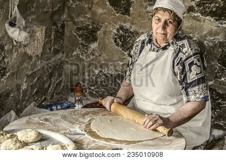 Ashtarak,armenia,19 Februar,2018: Armenian Woman Rolls Out The Dough A Wooden Rolling Pin Into Very 
