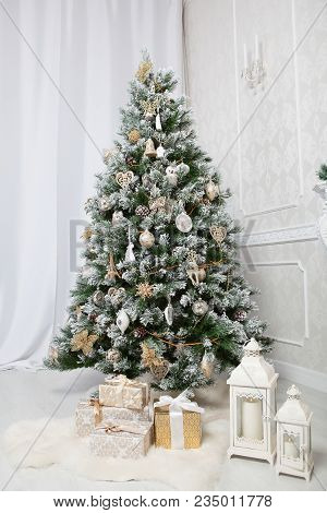 Decoration Christmas Tree With With Balls, Golden Flowers, Presenrs, White Furs And Candlesticks In 