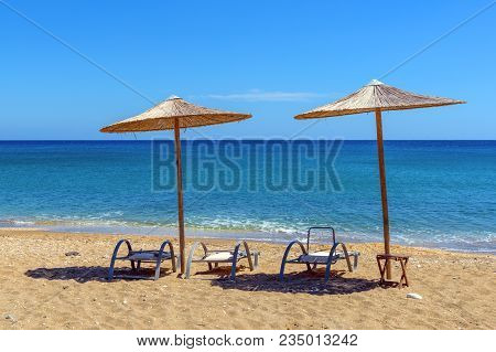 Sunbeds With Umbrellas On Paleochori Beach In Sunny Day On Milos Island. Cyclades, Greece.