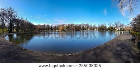 Panoramic View Of Semi-frozen Pond At Lease Park In Newcastle, Uk On An Early Spring Sunny But Cold 