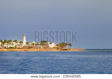 Seashore View With Building And Small Tower On The Beach.