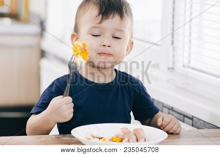 A Child In The Kitchen Eats Eggs Or Omelets In The Afternoon
