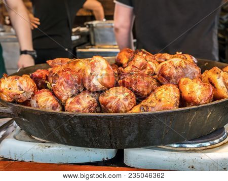 Big frying pan full of red meat chops, placed on oven