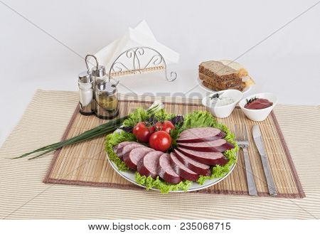 Smoked Sausage With Tomatoes And Lettuce Leaves On A Plate.  Can Be Used In Advertising And In The D