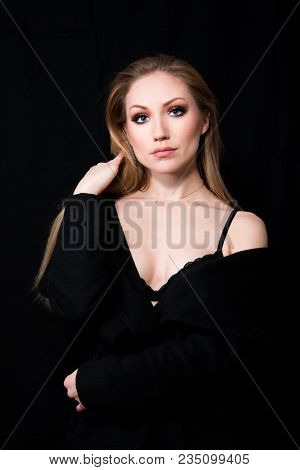 Sexy Lady Diva With Long Blonde Hair In Long Coat Posing In Studio, Dark Background. Elegant Woman. 