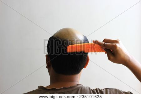 Bald Man In Isolated White Background Trying To Comb His Hair. View From Behind