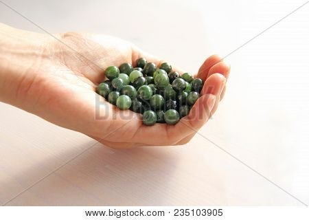 Natural Green Jade Nephrite Mineral Stones Beads. The Green Jade Stone Lies In The Hands. Hands Hold