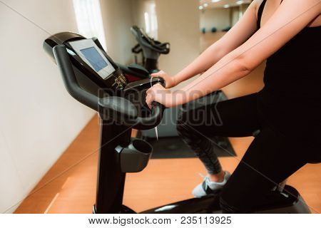 Close-up Portrait Of Fitness Woman Working Out On Bike Cyling Machine In The Gym.