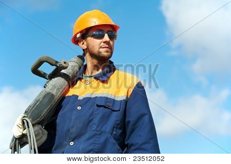 Portarait di positivo lavoratore Builder con martello pneumatico trapano attrezzature sopra cielo blu