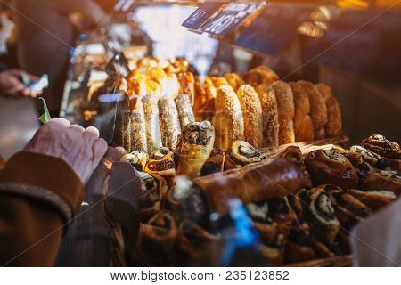 Senior Woman Buying Pies In Store. Retired Woman Holds Money Beside Showcase With Bakery Products. L