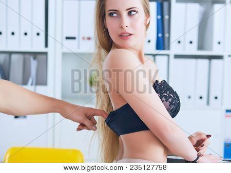 Man's Hand Pulls Bra Out Of The Beauitiful Secretary In Office Background. Flirt Or Harassment Conce
