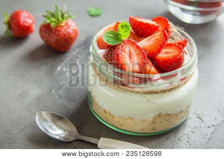 Strawberry Cheesecake In Glass Jar With Fresh Strawberries And Cream Cheese  On Grey Concrete Backgr