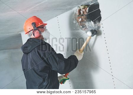 demolition work and rearrangement. worker with sledgehammer destroying wall