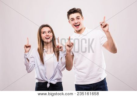 Happy Casual Couple Pointing Up To Something On White Background
