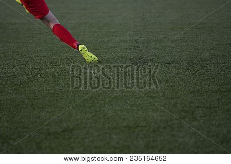 The Football Player Is Shooting The Football Ball On Artificial Turf Field.