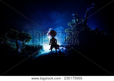 Horror Halloween Decorated Conceptual Image. Alone Girl With The Light In The Forest At Night. Silho