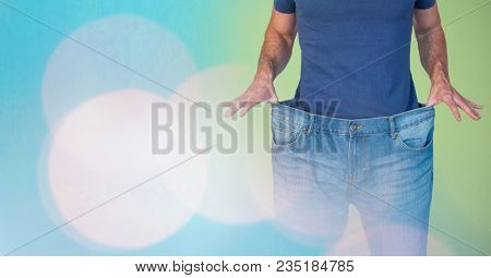 Mid section of man holding loose jeans representing weight loss and standing against abstract backgr