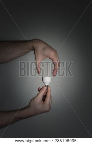 The Concept Of A New Idea Is A Light Bulb, Shown With The Help Of Male Hands And A Socle