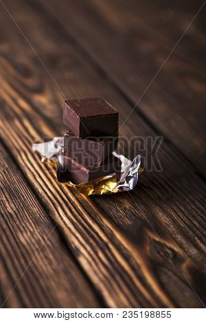 Pyramid Of Black Chocolate Pieces On Dark Old Wooden Background In Moodle Style