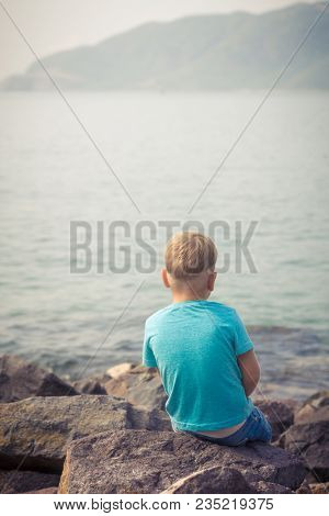 Cute caucasian boy at seaside. Rear view. Leisure time