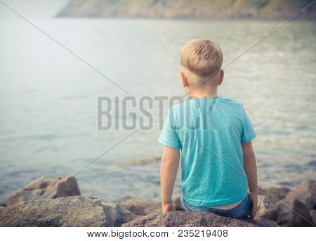 Cute caucasian boy at seaside. Rear view. Leisure time