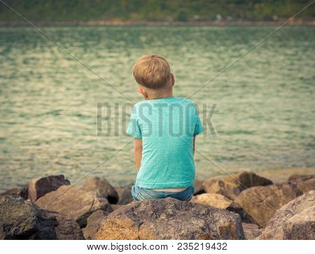Cute caucasian boy at seaside. Rear view. Leisure time