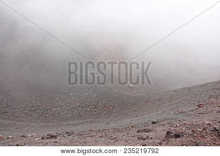 The Etna Volcano. Black Volcanic Earth And Thick Fog On Mount Etna. Place For Text. The Island Of Si