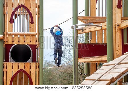 Happy Boy Climbing Rope On The Playground Outdoors