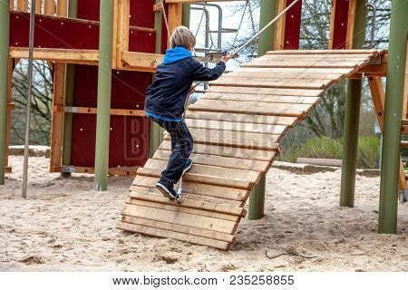 Happy Boy Climbing Rope On The Playground Outdoors