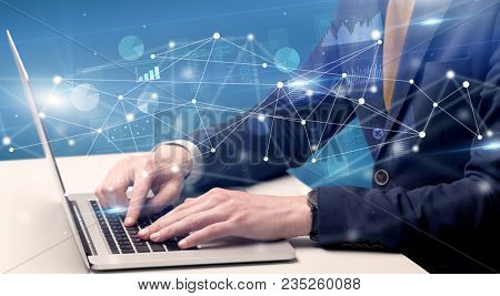 Businessman typing on laptop with linked reports charts grapghs around
