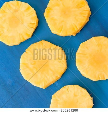 Close Up Patter Of Many Pieces Of Yellow Pineapple Laying On Blue Wooden Table Background.