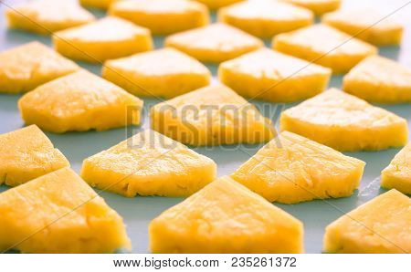 Close Up Patter Of Many Pieces Of Yellow Pineapple Laying On Blue Wooden Table Background.