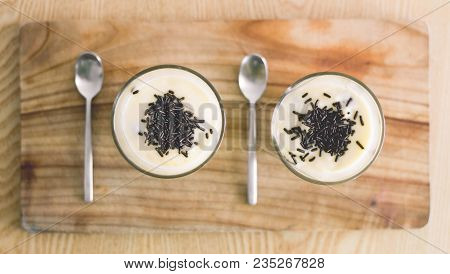 Two Vanilla Puddings On The Wooden Cutting Board. Two Desert Spoon.